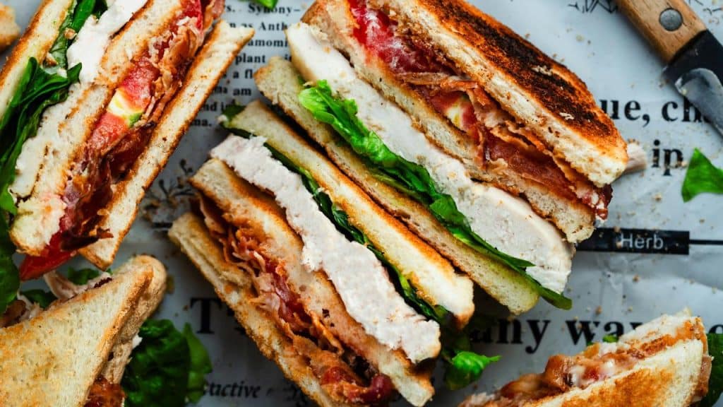 A club sandwich with bacon, lettuce, tomato, and turkey slices.
