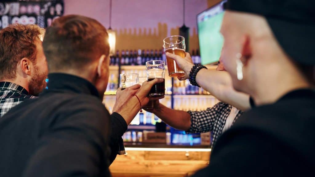 A group of people clinking beer glasses at a bar.