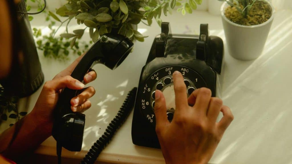 A person’s hand dialing an old rotary phone.