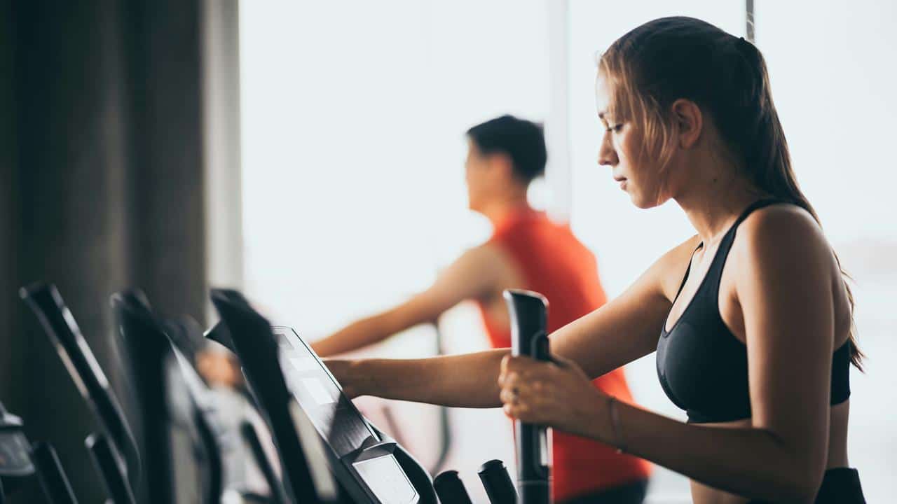 A woman using an elliptical machine in a gym.