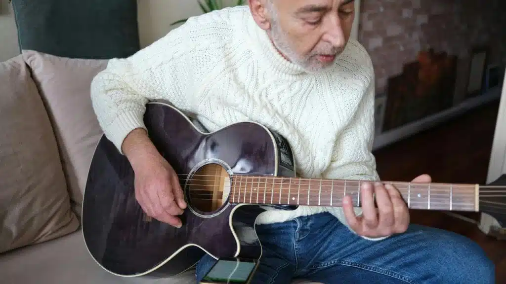 An older man playing an acoustic guitar.