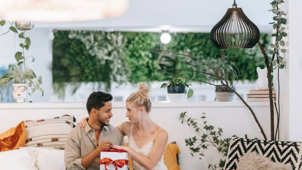 A woman surprising a man with a gift he mentioned liking