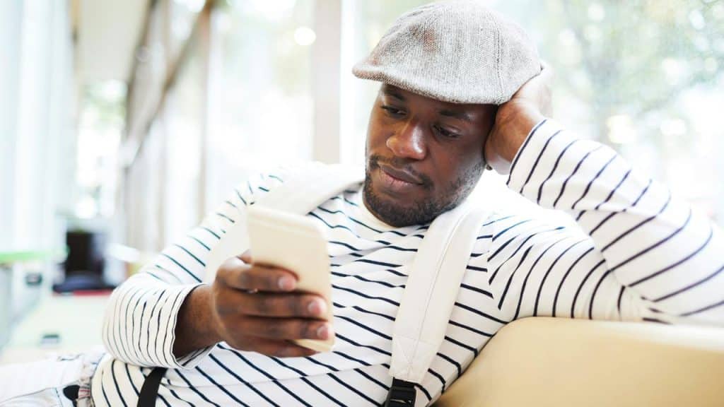A man in a flat cap looking at his phone.
