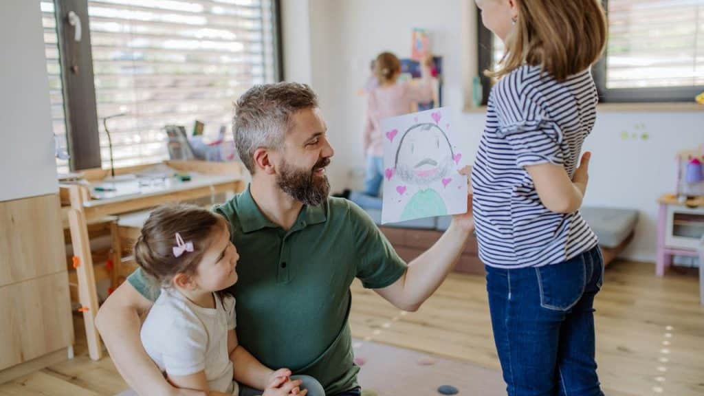 A father admiring his daughter’s heart-filled drawing.