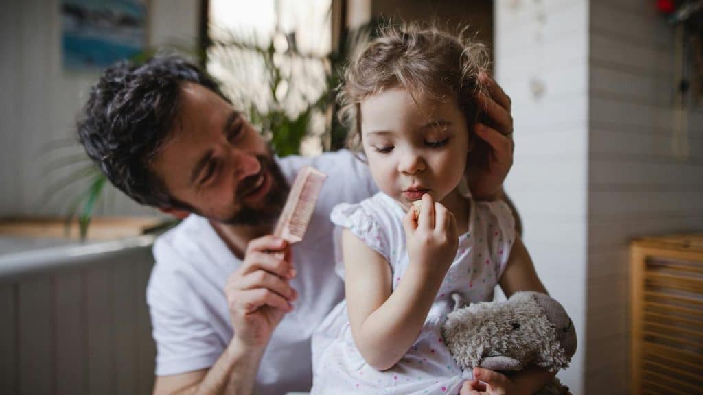 A man combing a little girl’s hair.