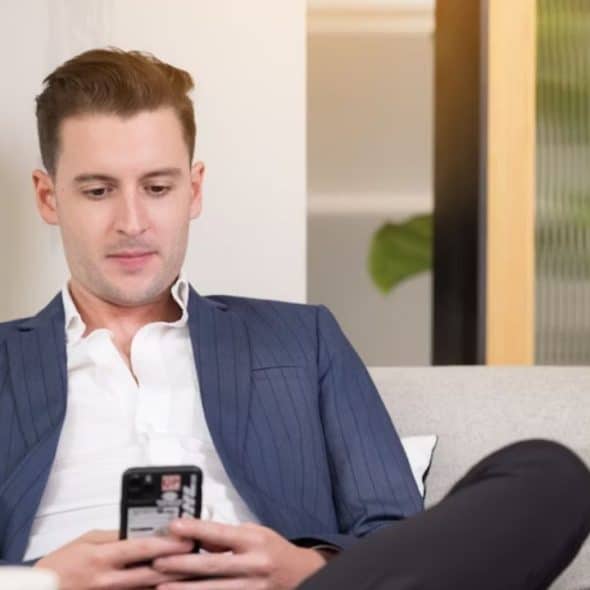 Man rethinking his daily “good morning” text while sitting on a sofa.