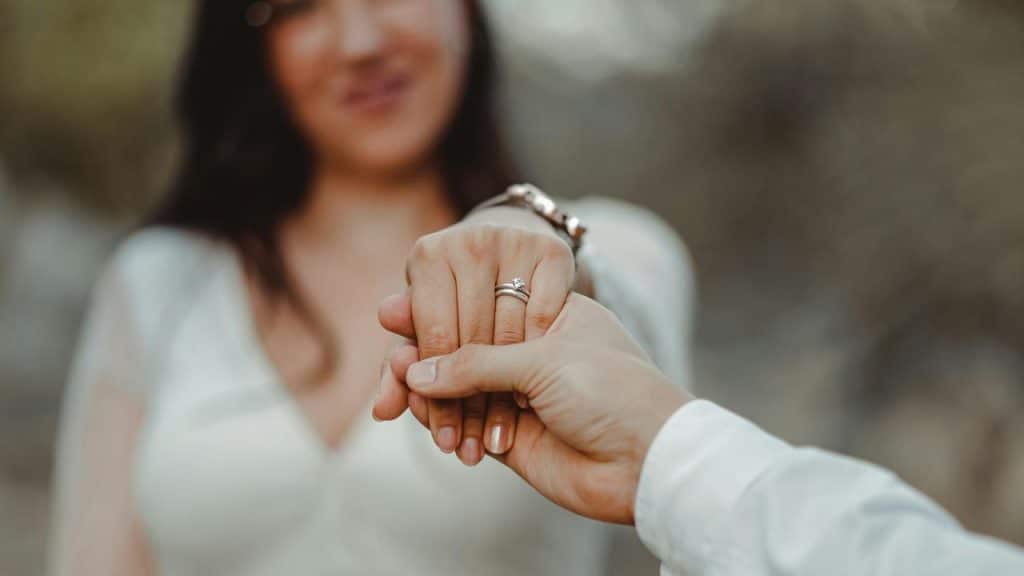 A couple holding hands with an engagement ring visible.