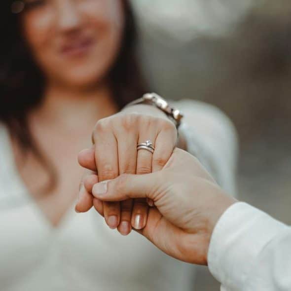A couple holding hands with an engagement ring visible.