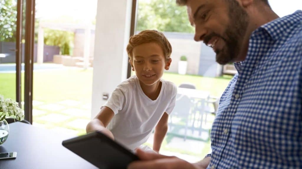 Dad talking to a kid about screen time with a tablet in hand.