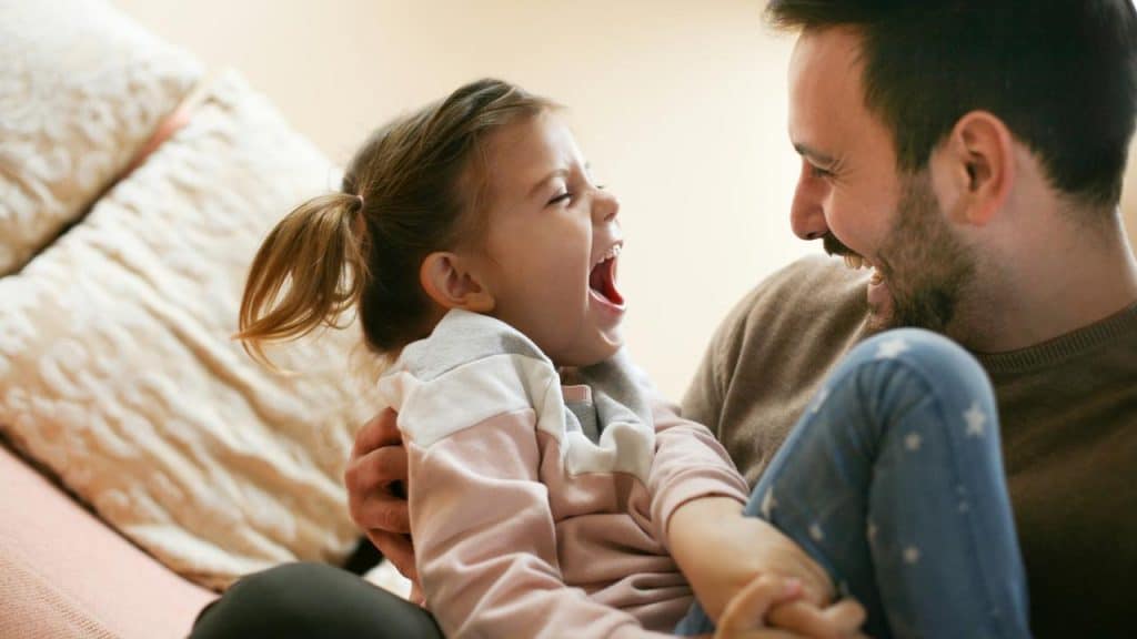 A father holding his laughing daughter.