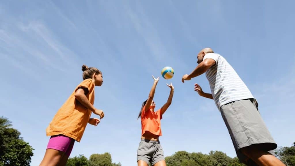 Father playing volleyball with his teens as a stress relief through wellness activities