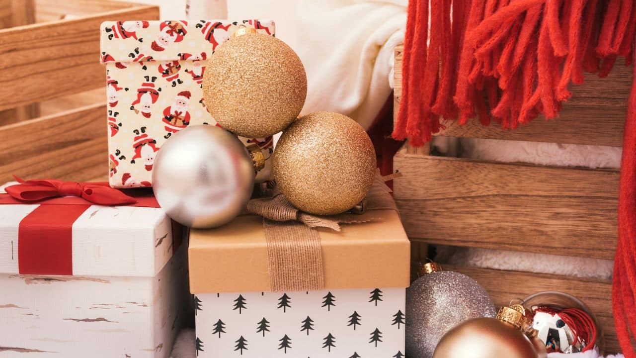 A close-up shows various Christmas decorations, including wrapped presents and ornaments, with wooden crates.