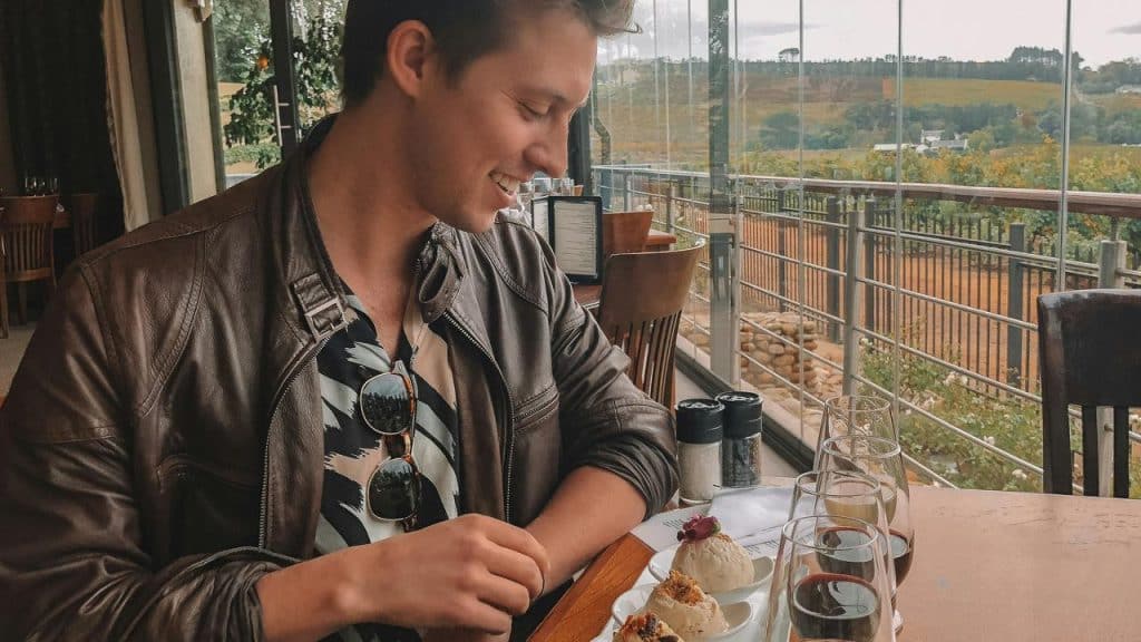 A man enjoying wine and appetizers at a vineyard table.
