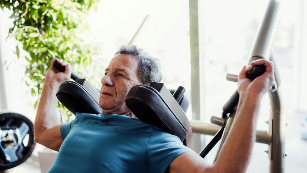 An older man working out on a chest press machine.
