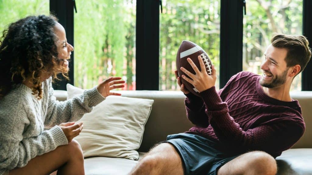 A couple on a couch passing a football.