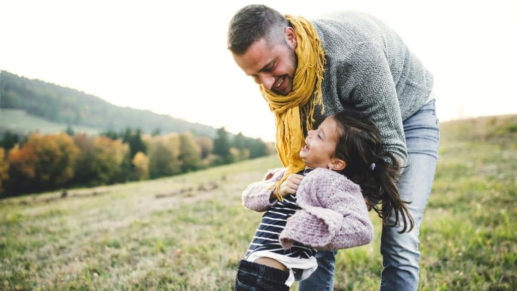 A man playfully lifting a child in a field.