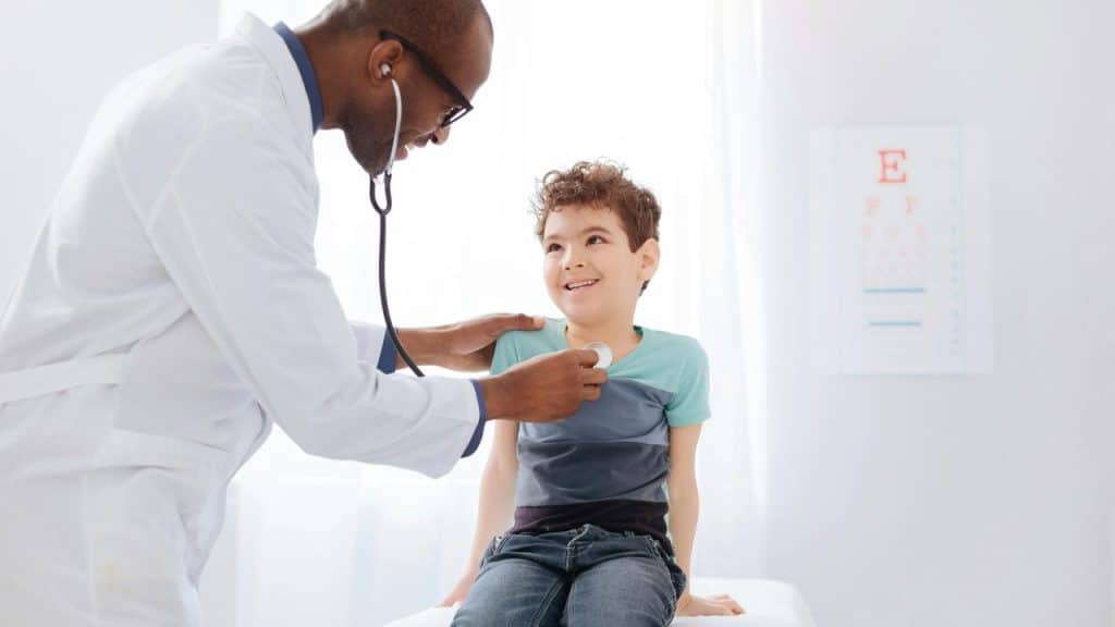 A doctor listening to a boy’s chest with a stethoscope.