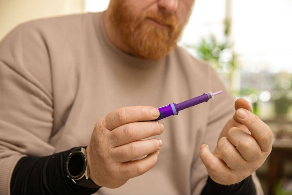 A picture of a man holding an injection for diabetes