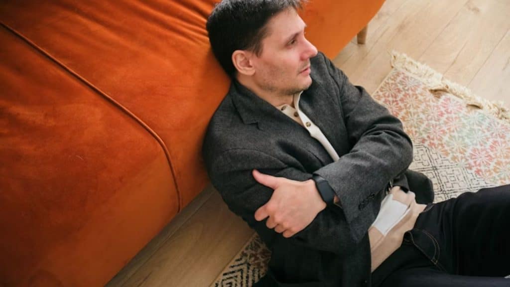 Man sitting uncomfortably, holding stomach dealing with constipation.