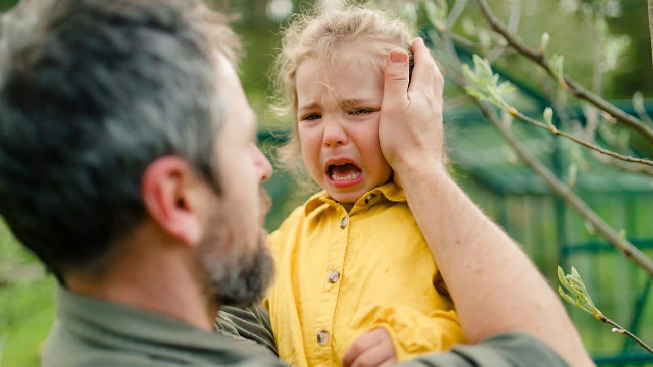 A man comforting a crying toddler.