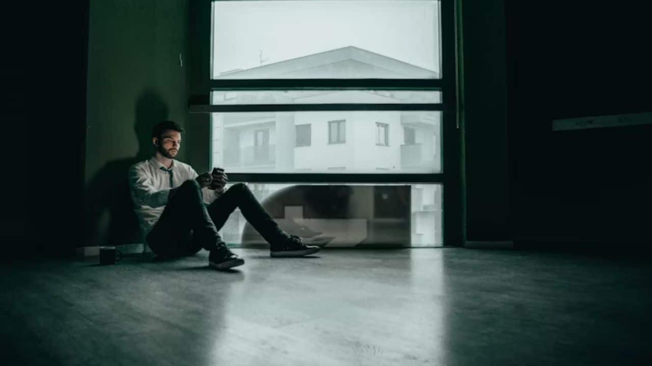 A man tearing up while sitting alone at home allowing space to process deep emotional pain.