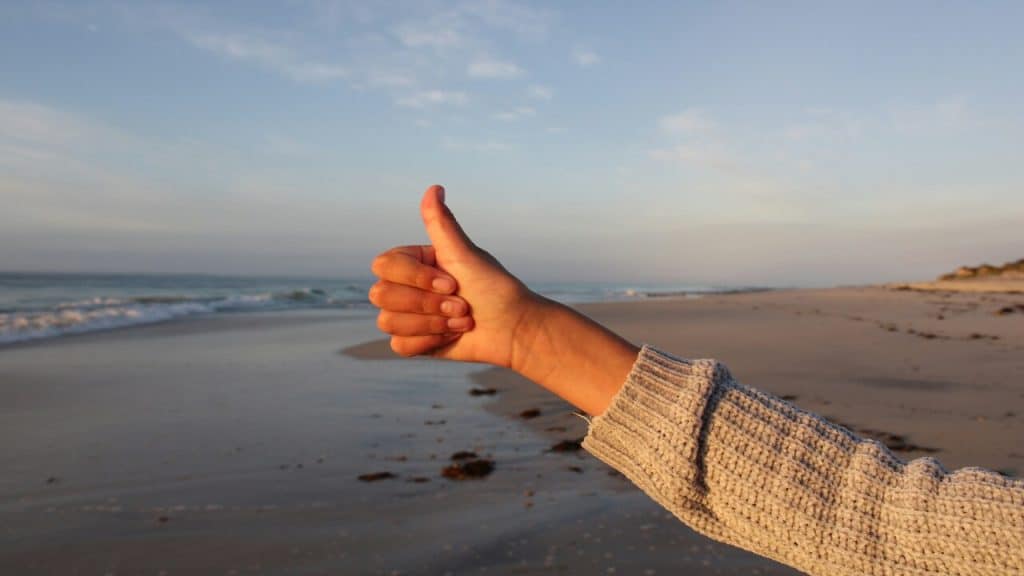 A person doing a thumbs up on the beach
