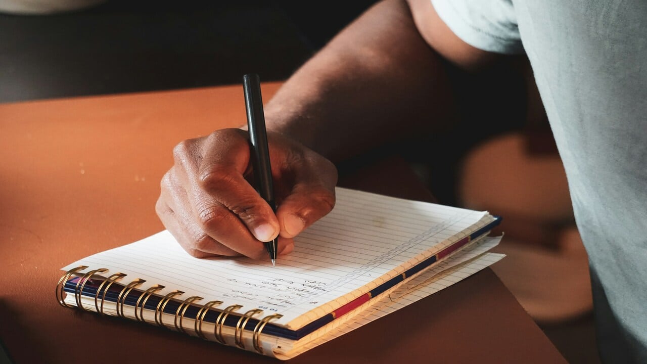 A man writing on a notebook.