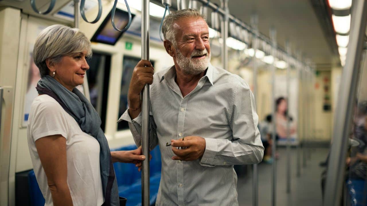 A happy senior couple rides a train, looking out the window.