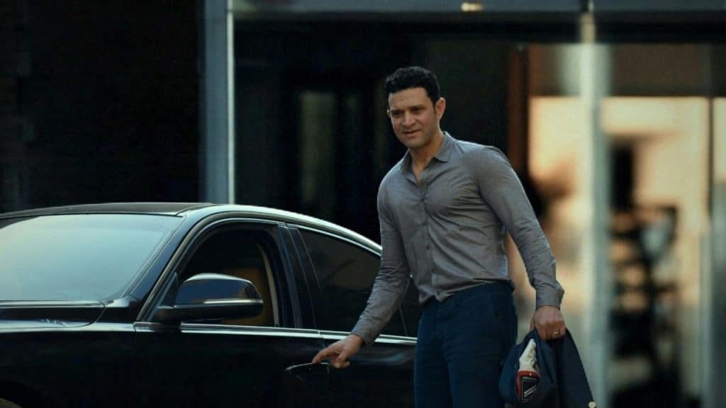 A man opening a car door while holding his jacket and hat.