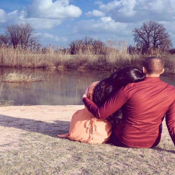 A couple hugging while looking at a body of water