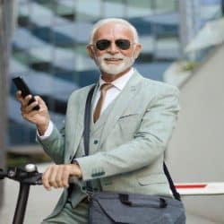 A handsome older man riding a scooter