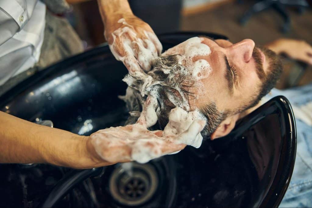 A man getting his hair shampooed to a parlor