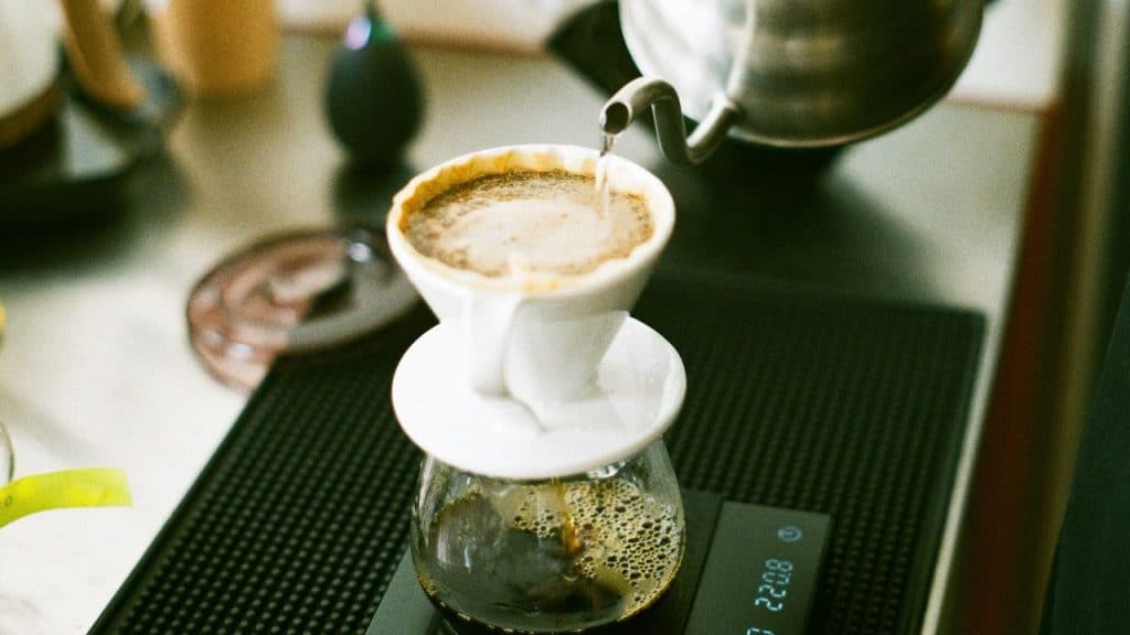 A high-angle shot of a person pouring hot water into a pour-over coffee maker.
