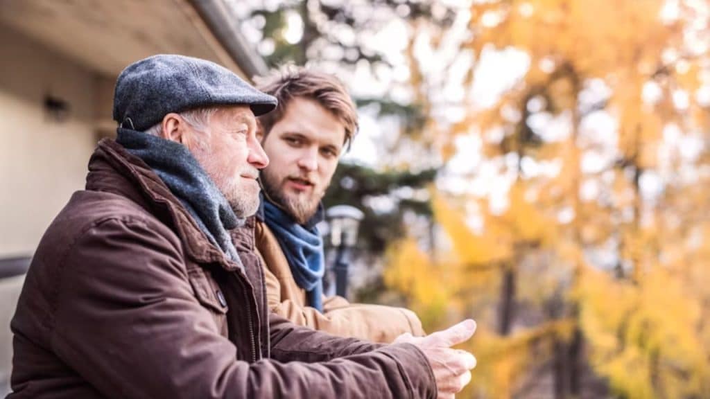 Man animatedly chatting about weather  with neighbor patterns on the front porch
