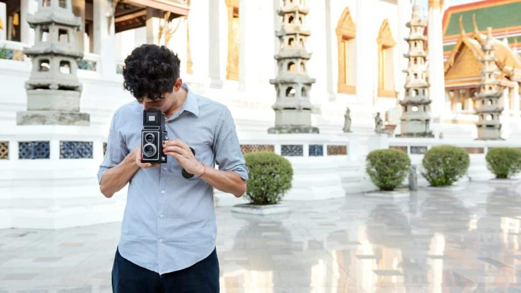 A man using a vintage camera in a temple courtyard.