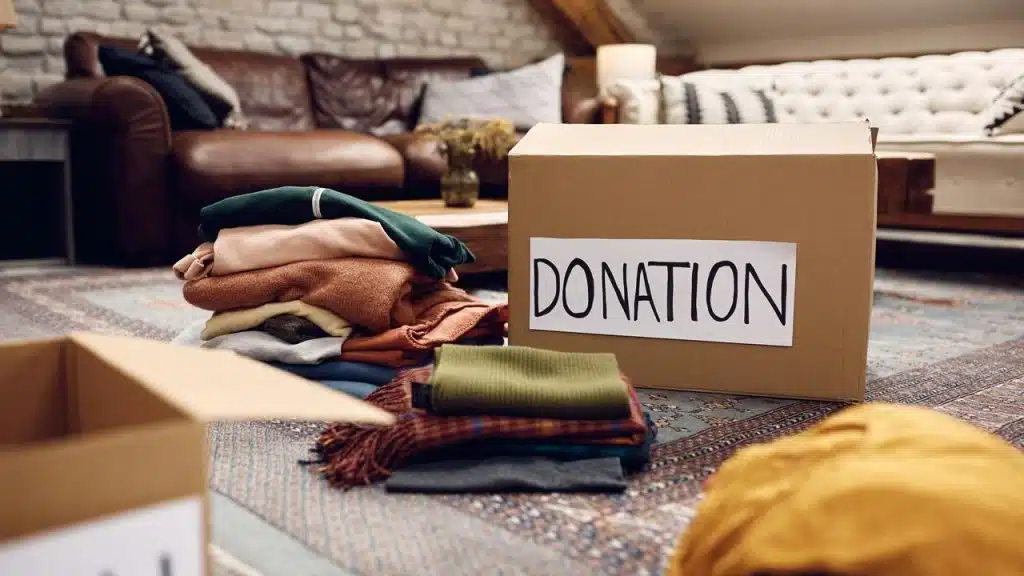 A donation box beside folded clothes in a living room.