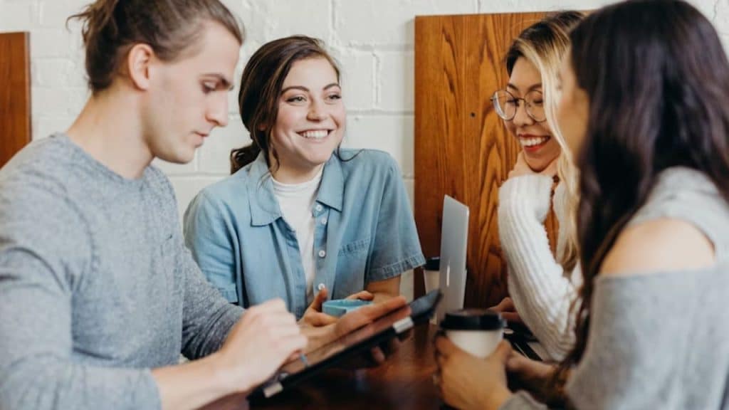 Woman laughing with friends while man sits nearby feeling left out
