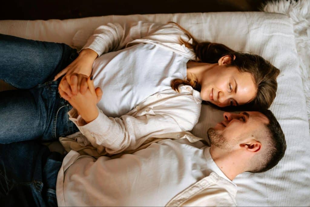 A man and woman laying at the bed