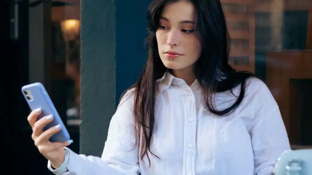 Woman reading a text on her phone with a neutral expression.