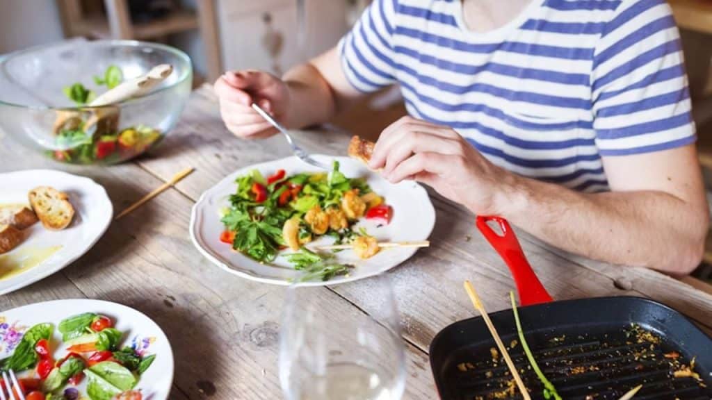Healthy man eating a balanced meal with both protein and vegetables.