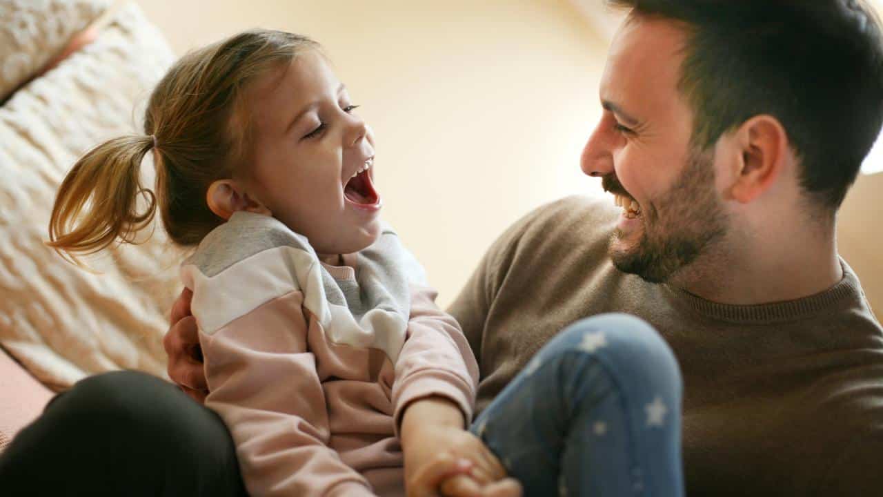 A father holding his laughing daughter.