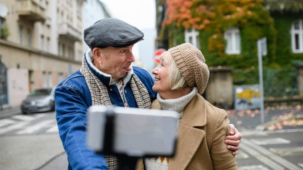 An older couple taking a playful selfie on a city street.