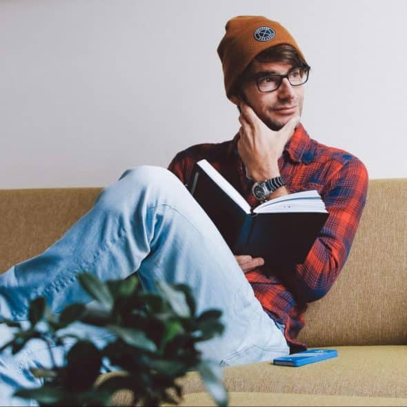 A man holding a book while thinking.