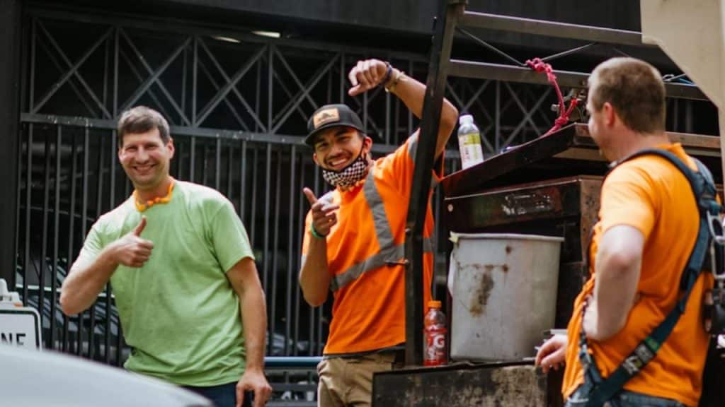 Group of men smiling while working together in cleaning a public space