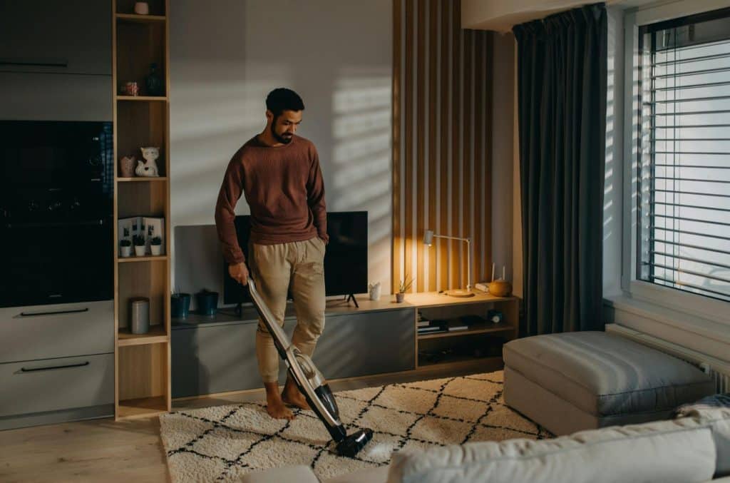 A man cleaning a living room.