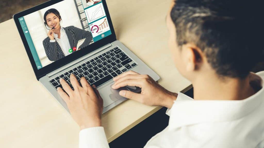 A person video chatting on a laptop with a woman wearing a headset.