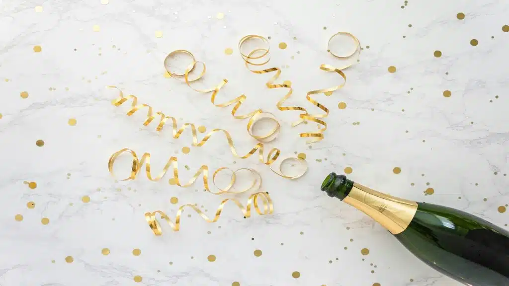 Gold confetti coming out of a champagne bottle