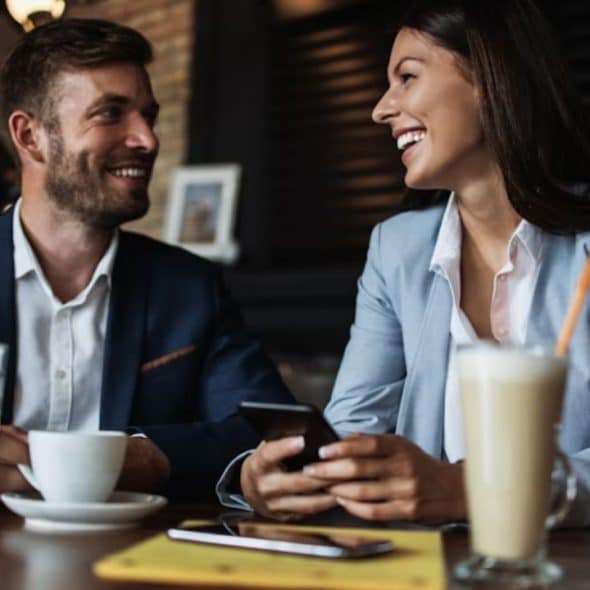 A man smiling warmly at someone across a café, keeping body language relaxed