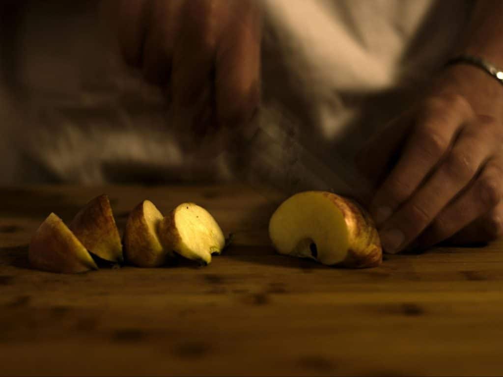 A man slicing an apple.
