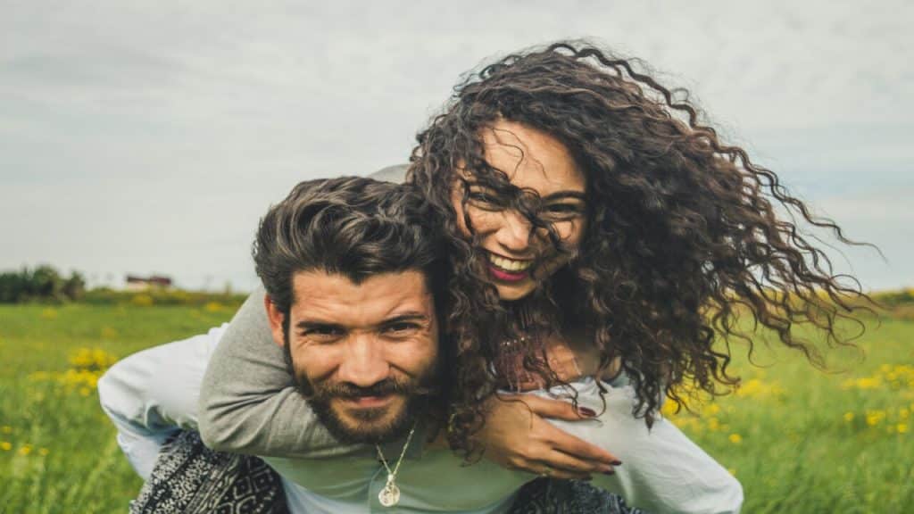 A couple laughing on a field of flowers